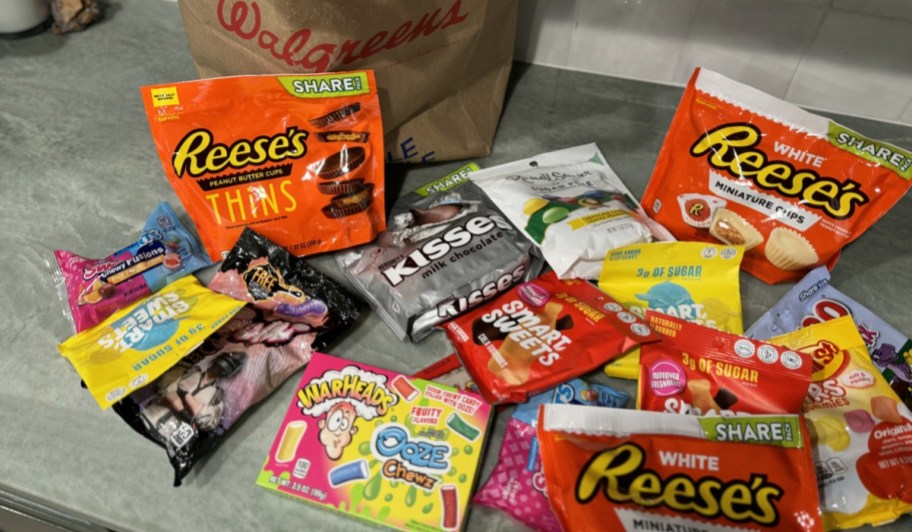 lots of bags of candy on countertop with walgreens grocery bag