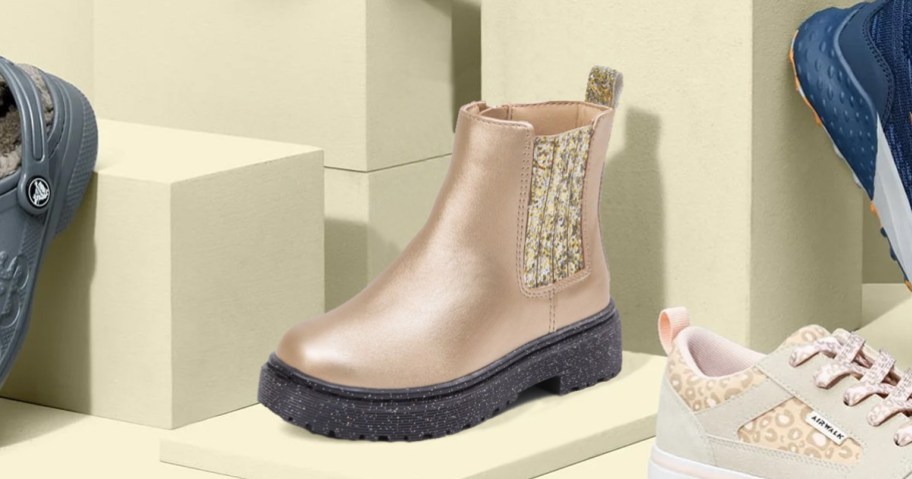 metallic gold boot with glitter details on display with other shoes