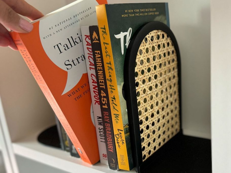 hand pulling books off rattan bookends 