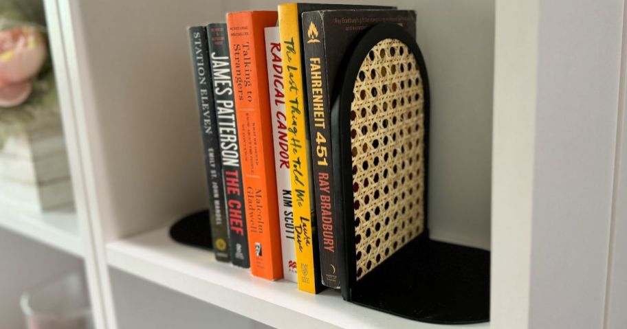Bookshelf with books held between metal and rattan bookends