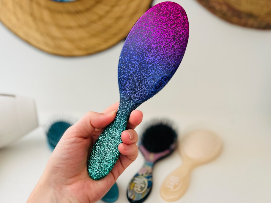 hand holding up a sparkly wet brush with more brushes in background