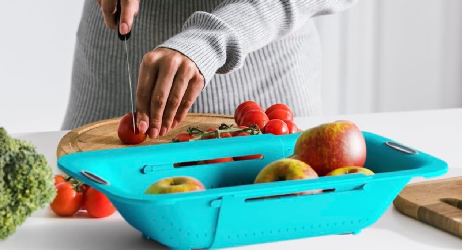 Woman chopping veggies into colander she will use to wash them