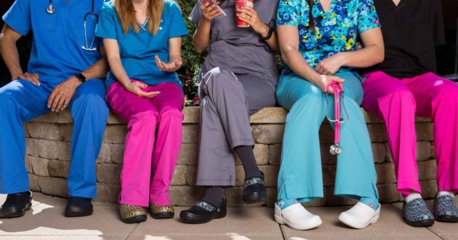 Hospital staff sitting together in a line all wearing Crocs