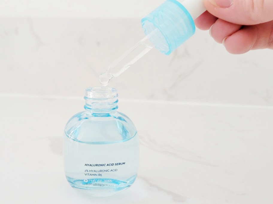 hand pulling the dropper out of a blue bottle of hyaluronic acid serum