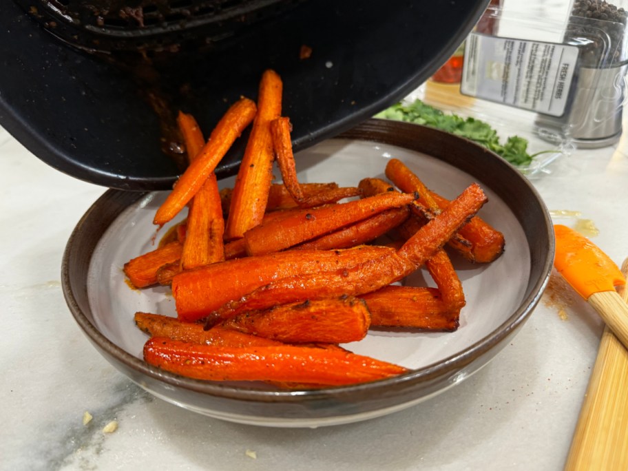 adding carrots to a plate after cooking in an air fryer