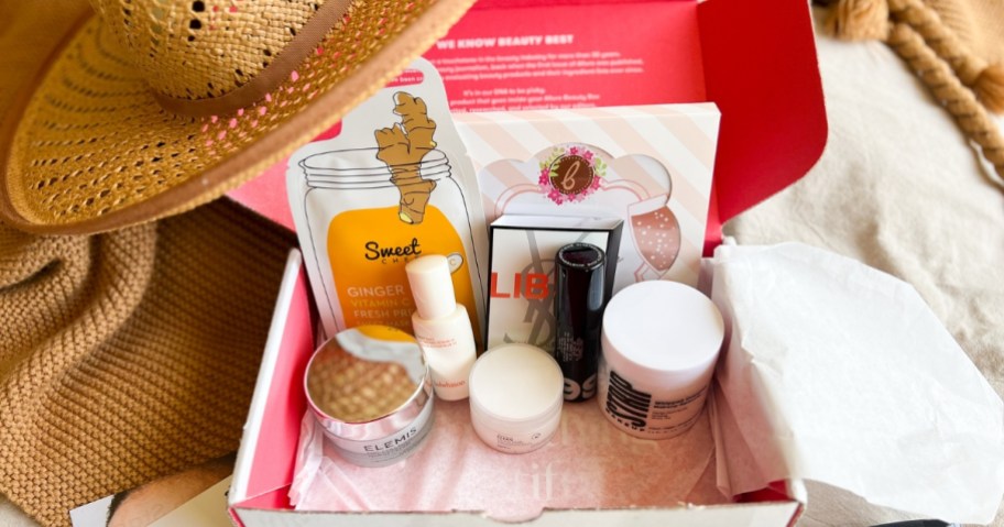 red open Allure beauty box showing various skincare and makeup items, hat leaning against the box