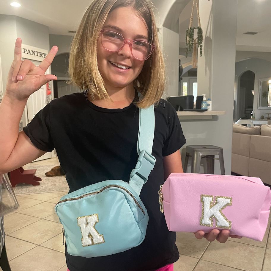 girl holding up blue and pink k monogram bags