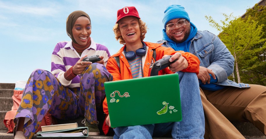 3 young adults using a green laptop