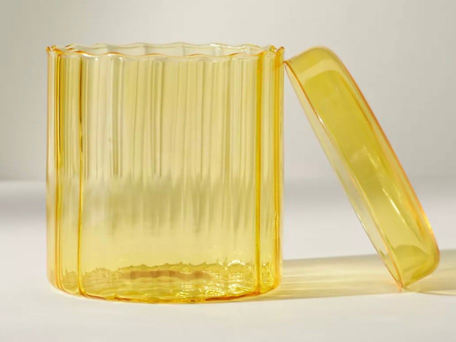glass yellow canister with lid sitting on side