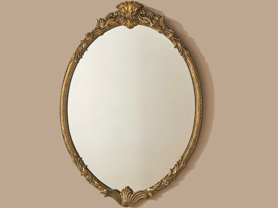 gold oval mirror hanging on wall