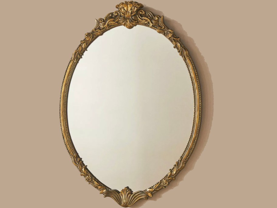 gold oval mirror hanging on wall