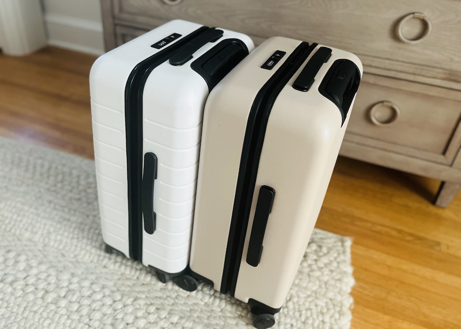 white and tan suitcases standing next to each other on beige rug