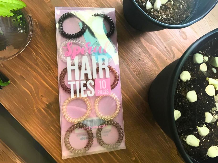 package of spiral coil hair ties laying on table with plants on each side