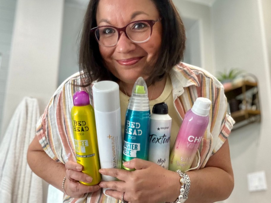 woman holding many hairspray cans