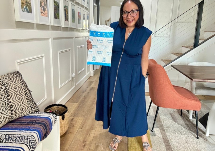 a woman wearing a blue dress holding an amazon shipper envelope