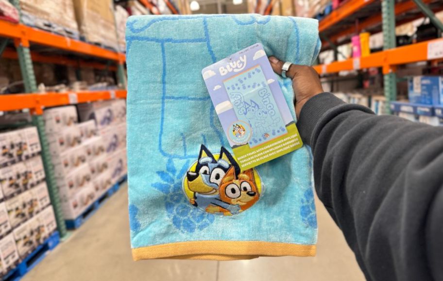 a womans hand holding a bluey beach towels in a costco store
