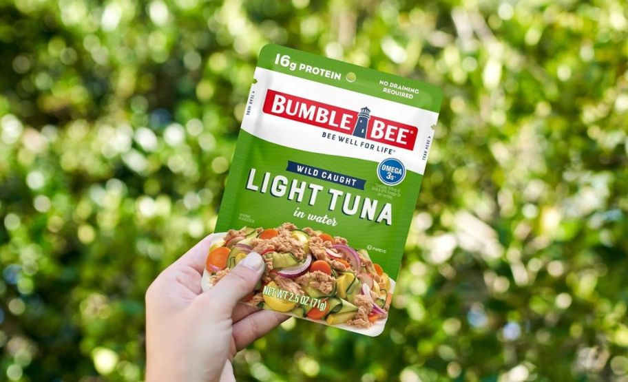 a hand holding a pouch of bumble bee tuna