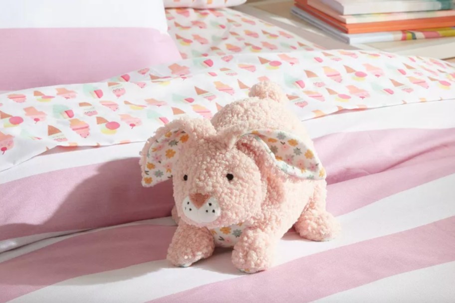 pink bunny pillow on pink striped bed