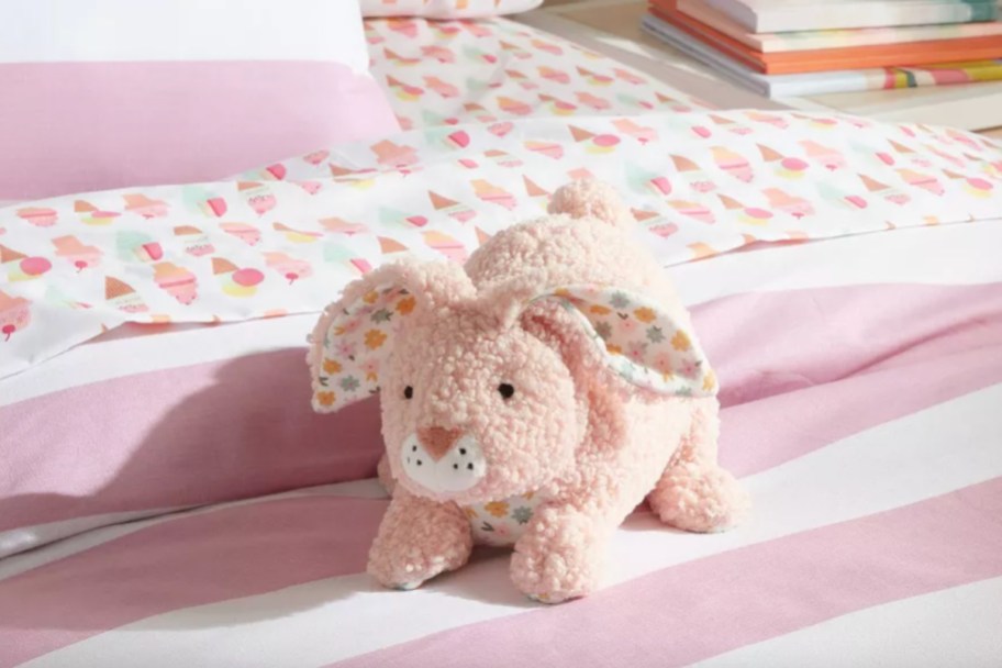 pink bunny pillow on pink striped bed