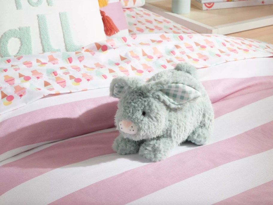 grey bunny pillow on pink striped bed
