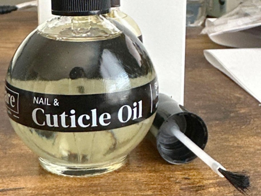 care c cuticle oil bottle with brush laying next to it on table