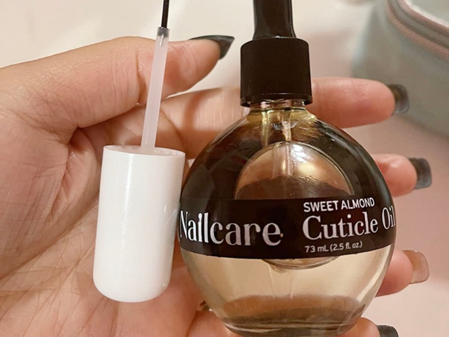 hand holding care c sweet almond cuticle oil bottle with brush 