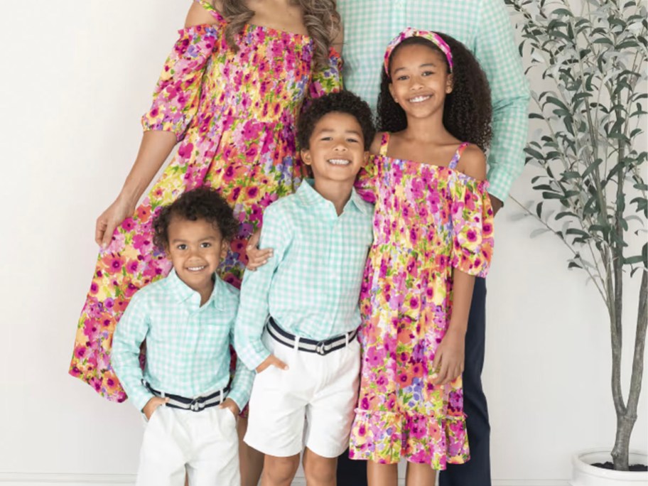 family wearing pink floral dresses, white shorts and teal shirts