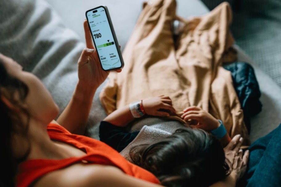 woman with daughter looking at credit karma on phone