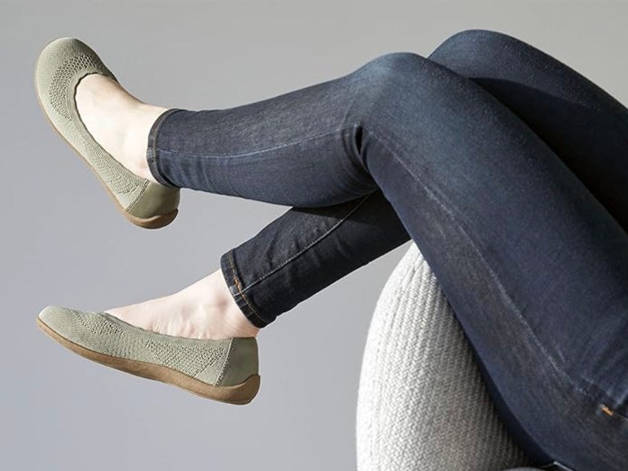 woman wearing green flats and jeans sitting on chair
