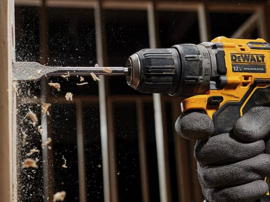 hand using yellow and black dewalt cordless drill on wood