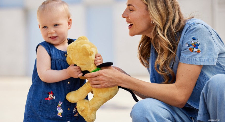 woman handing pluto toy to baby