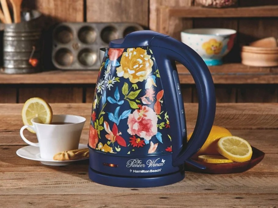 blue floral kettle sitting on kitchen table next to mug