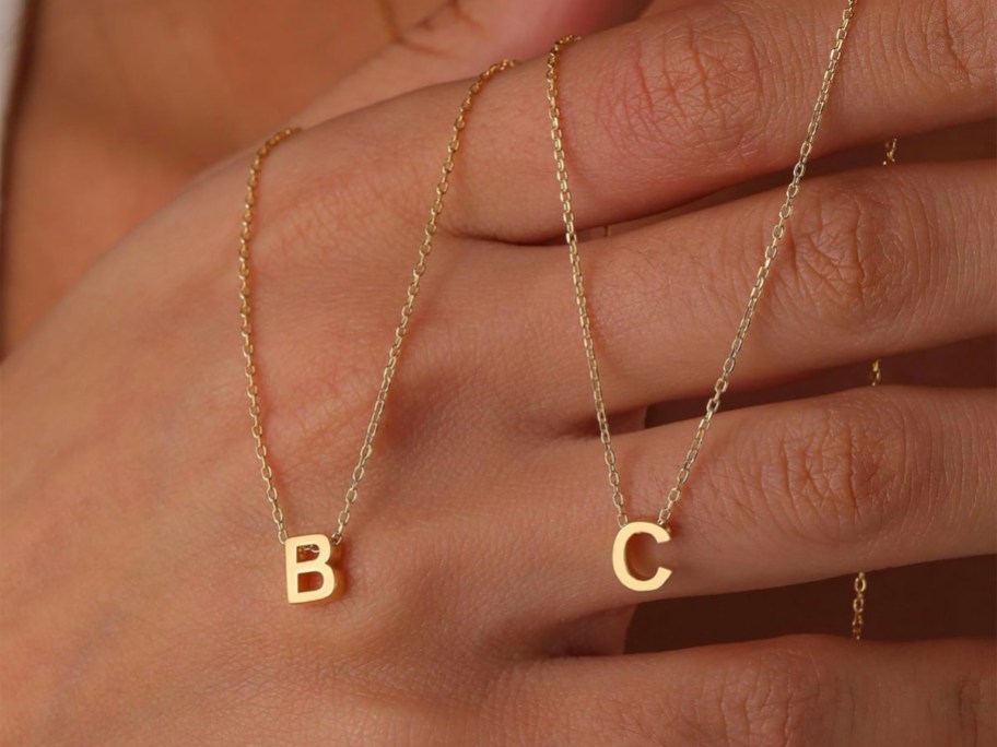 hand holding B and C necklaces 