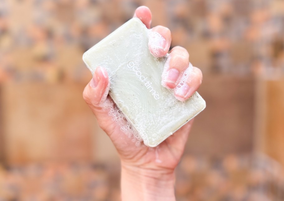 hand holding bubbly bar soap in shower