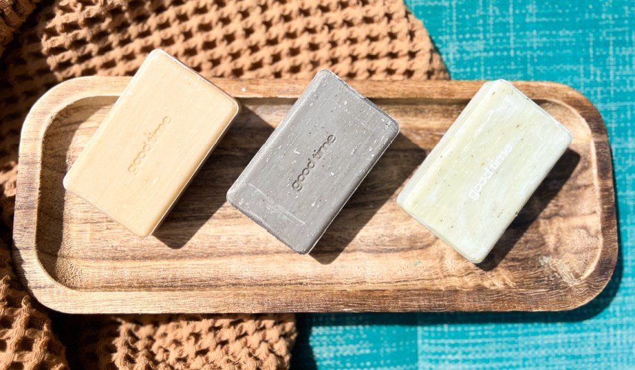 three bars of soap on wooden tray and waffle towel