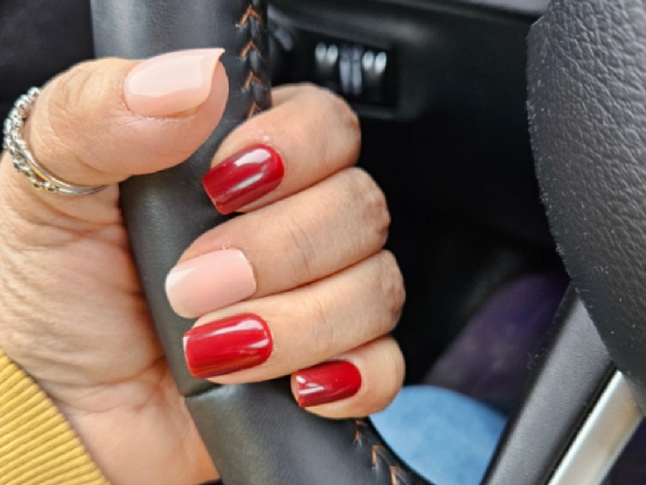 hand holding car driving wheel wearing nail tips