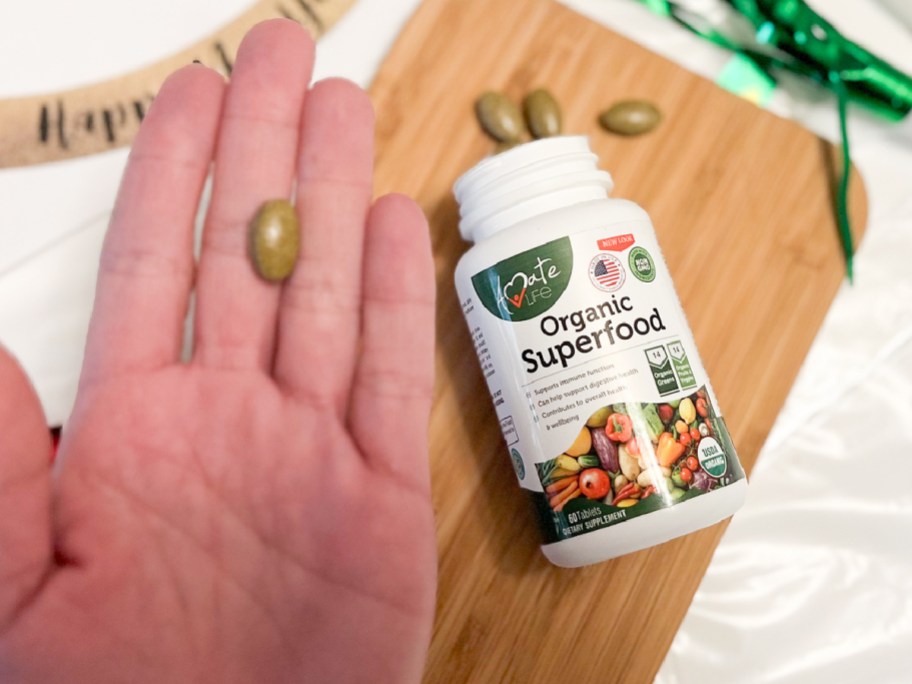 hand showing size of organic superfood pill with confetti in the background