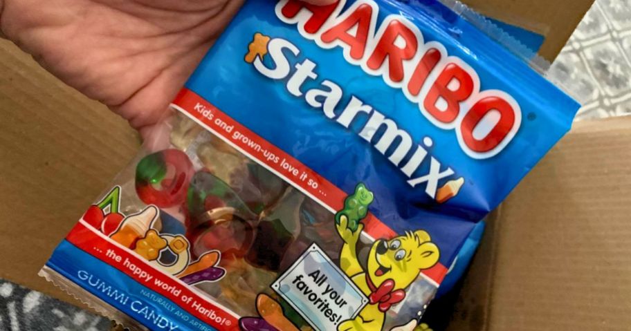 a mans hand holding a bag of haribo starmix gummi candy