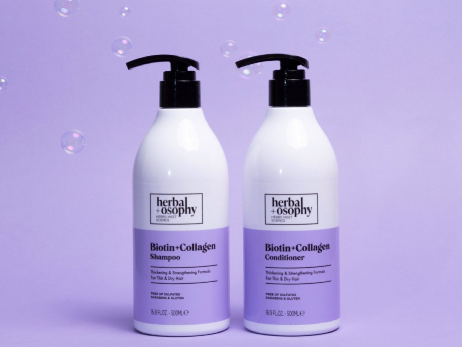 purple and white herbalosophy biotin and collagen shampoo and conditioner in front of a purple background with bubbles floating around