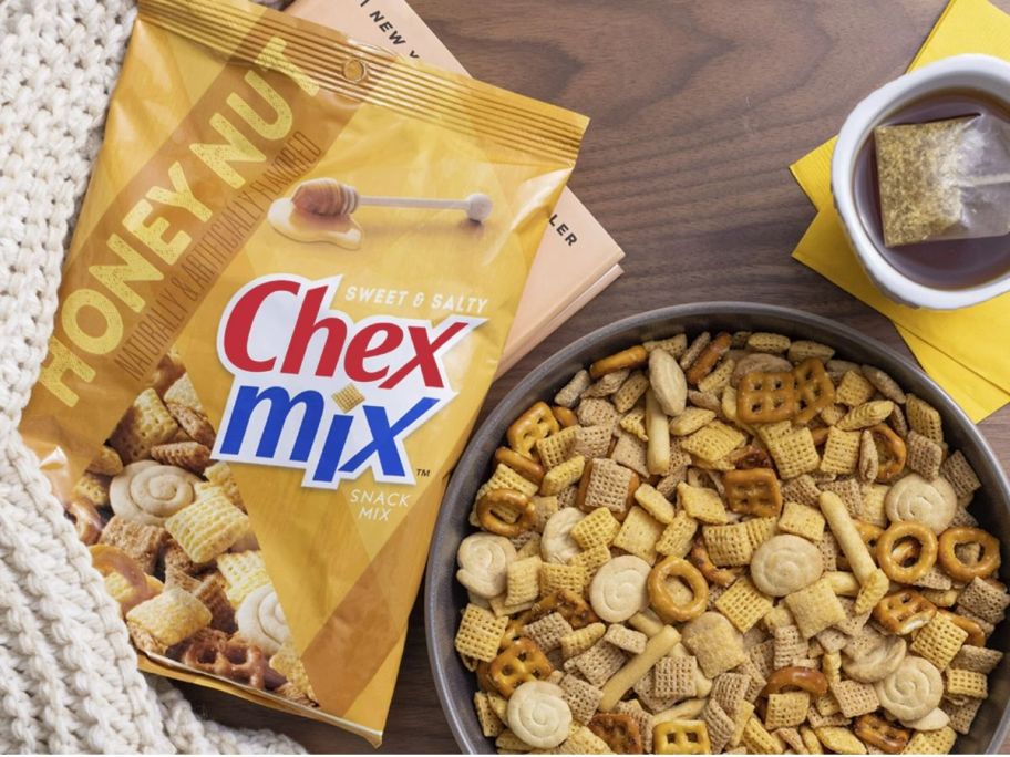 bag of honey nut check mix next to a large glass bowl of honey nut chex mix