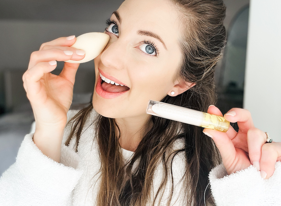 woman putting kosas concealer on undereye with white beauty sponge