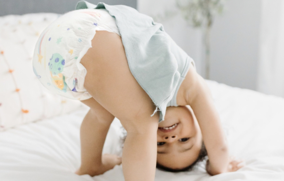 baby turned upside down in diaper smiling on bed