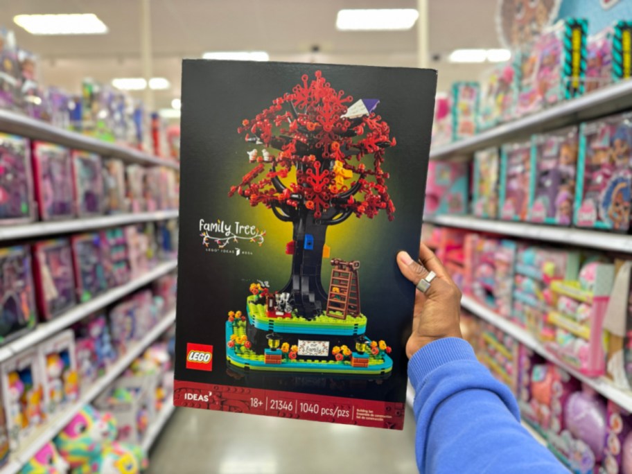 hand holding up a box with the LEGO Ideas Family Tree set in a Target store aisle