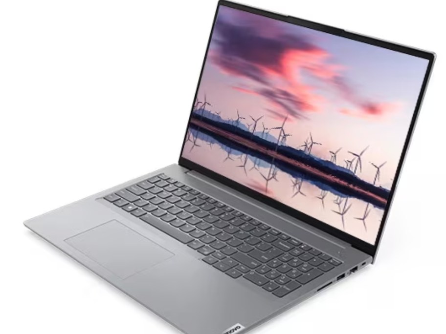 silver Lenovo laptop open showing the desktop with an image of a lake and a sunset