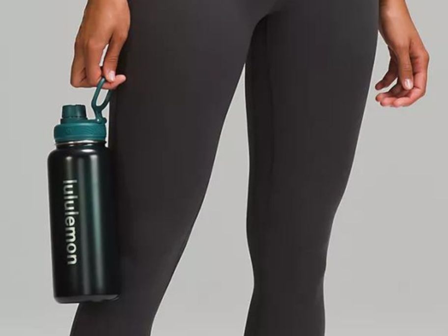 Stock image of a woman hold a lululemon water bottle by her legs