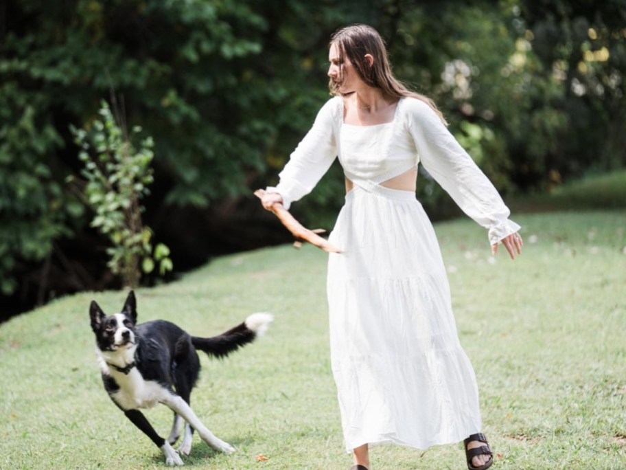 woman in white dress playing with dog outside
