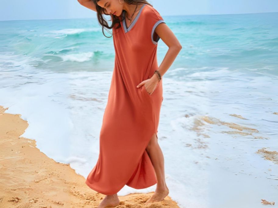 a woman walking on a beach wearing a caramel colored maxi drees