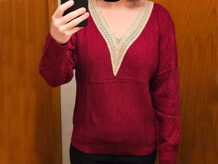 woman taking photo of herself wearing red v neck lace sweater 