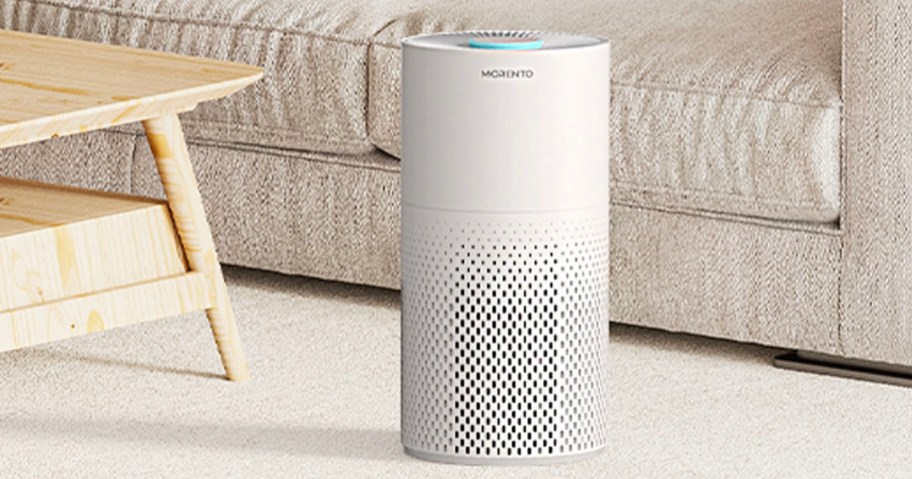 white morento air purifier sitting in front of couch next to coffee table