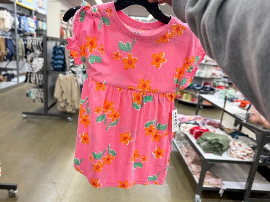 hand holding pink floral dress on hanger